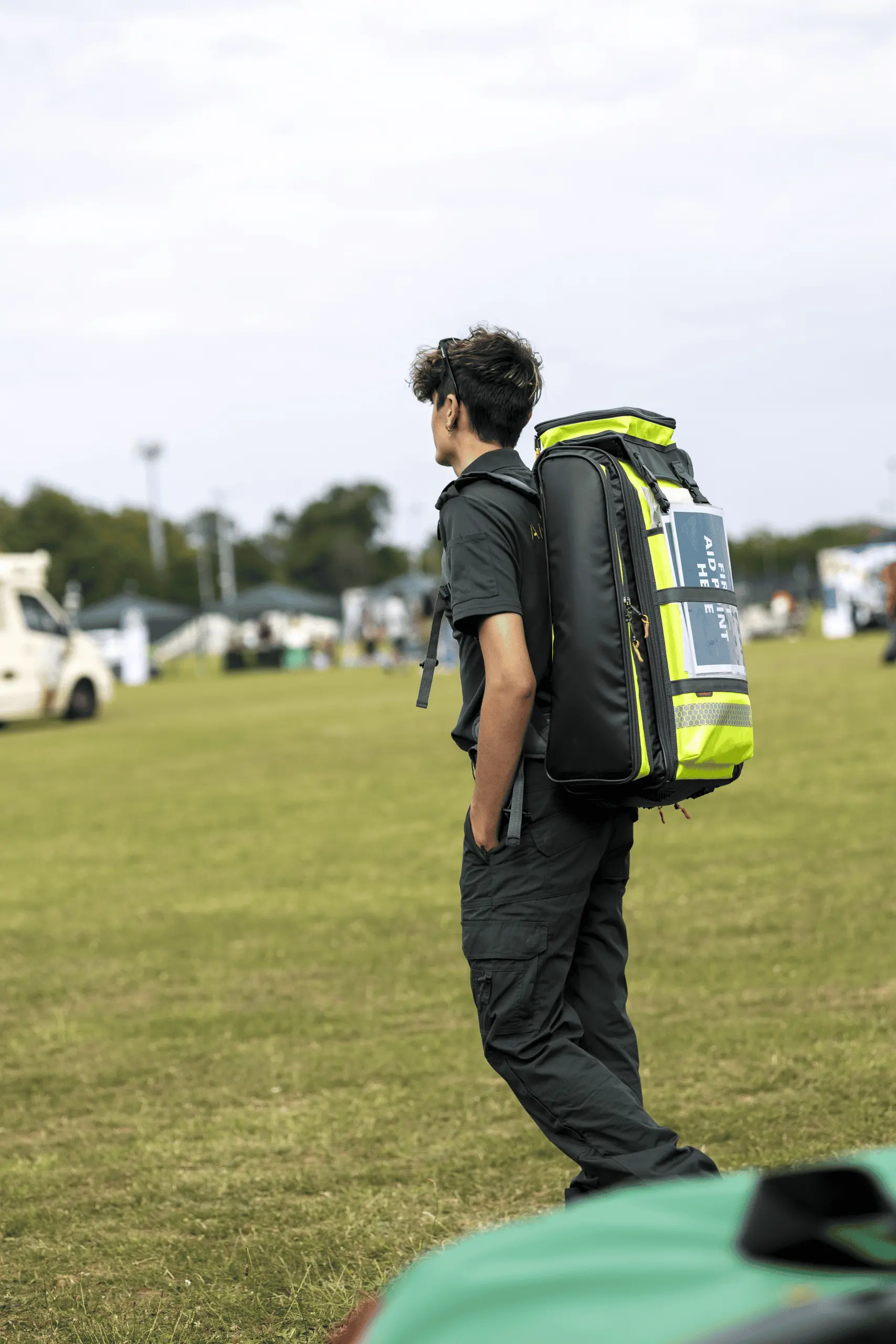 LightMed event medical responder walking across a grass event site carrying a high-visibility medical backpack.